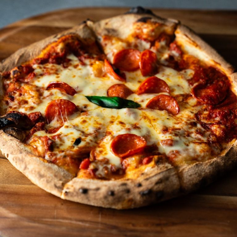 Pepperoni pizza with melted cheese on a wooden board.