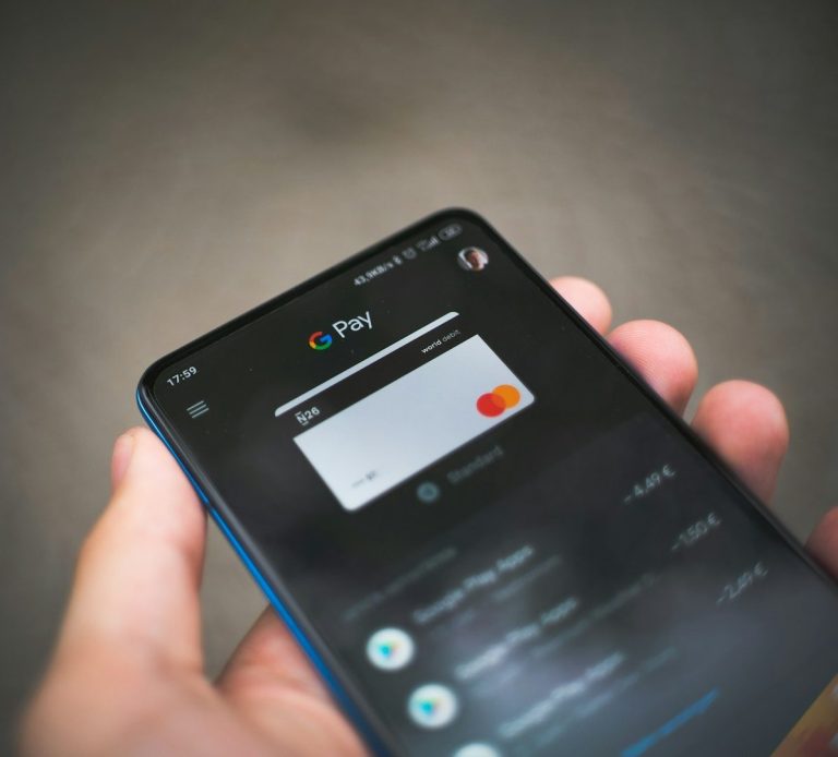 A hand holding a smartphone displaying a payment app with card details.