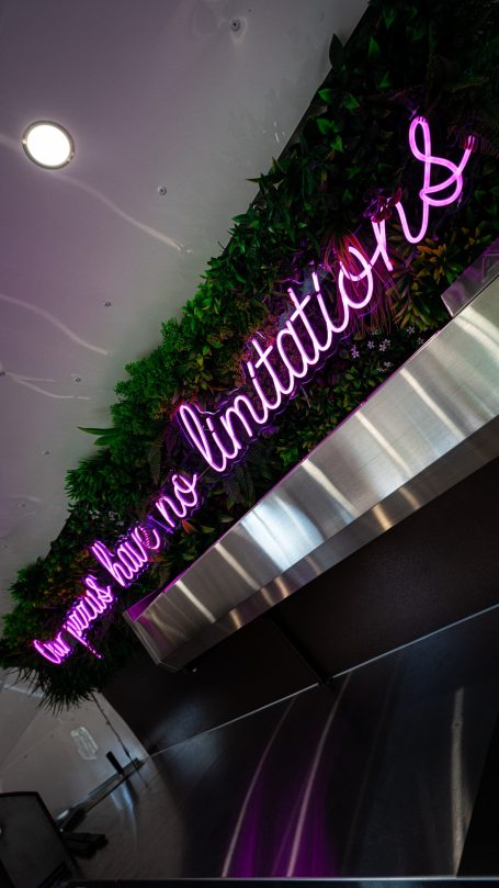 Neon sign on a green leaf wall reads "No limitations."