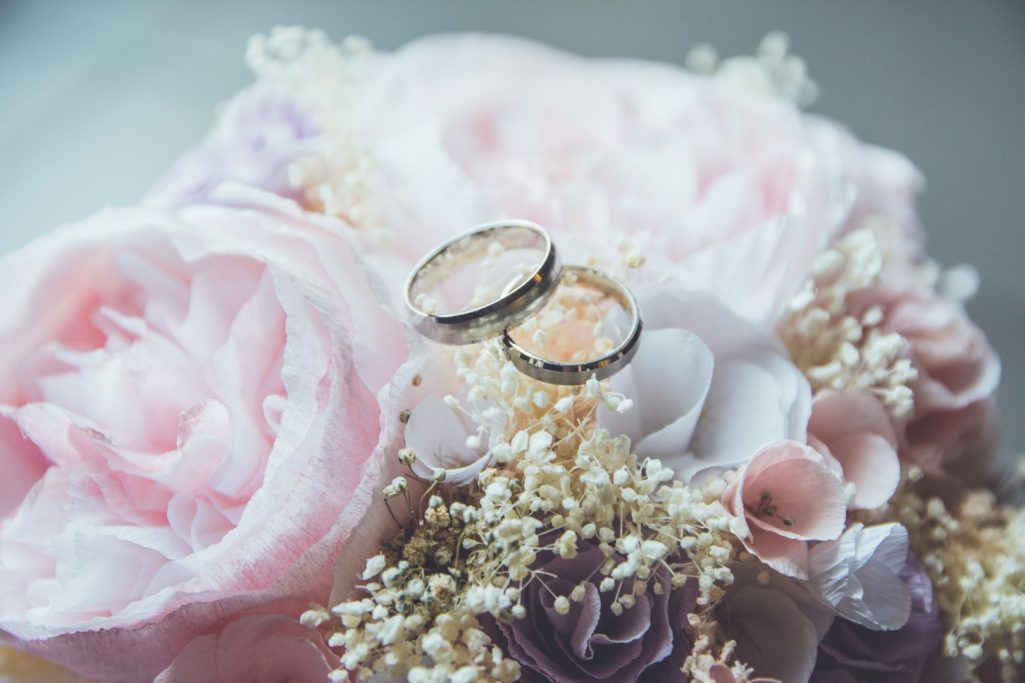 Two wedding rings nestled in a bouquet of pink and white flowers.